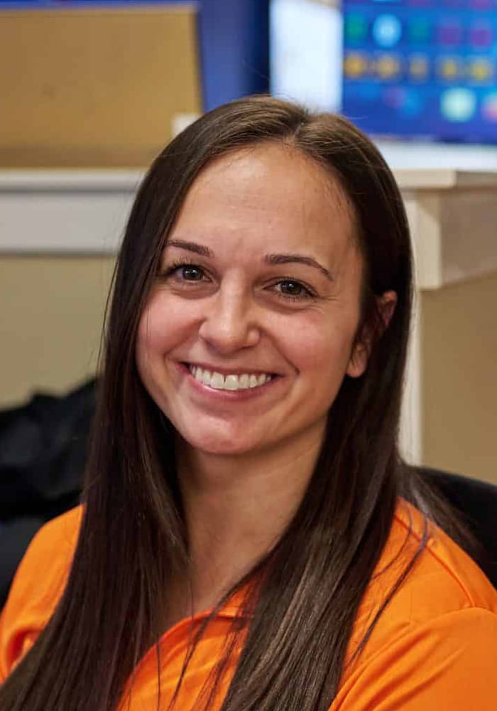 Arclight-Group_101_home_mobile | ArcLight Group Smiling woman with long dark hair in orange scrubs posed for a portrait in a clinical setting