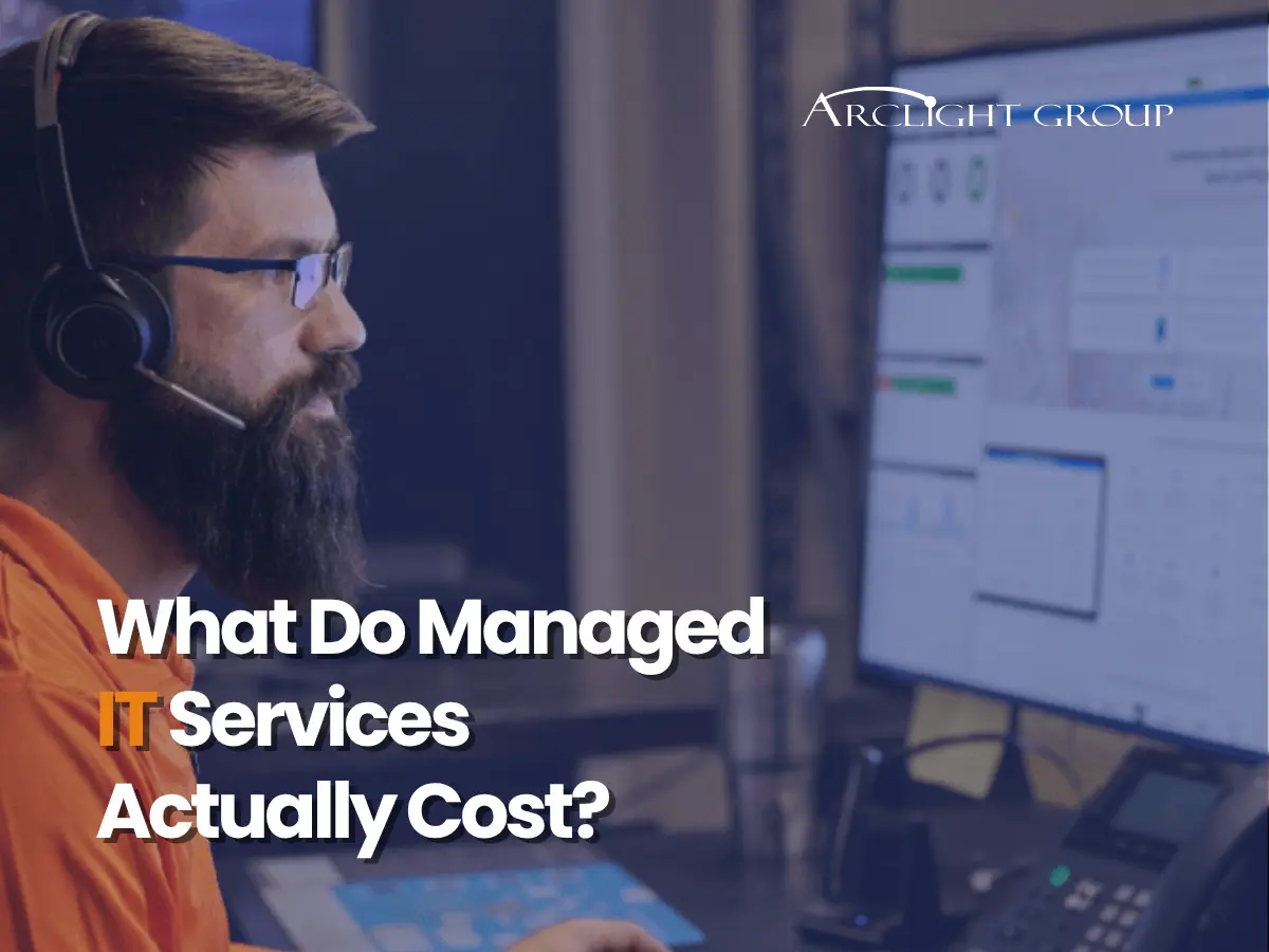 Man wearing a headset working at a multi-monitor setup with the Arclight Group logo, overlaid text asks about the cost of managed IT services.