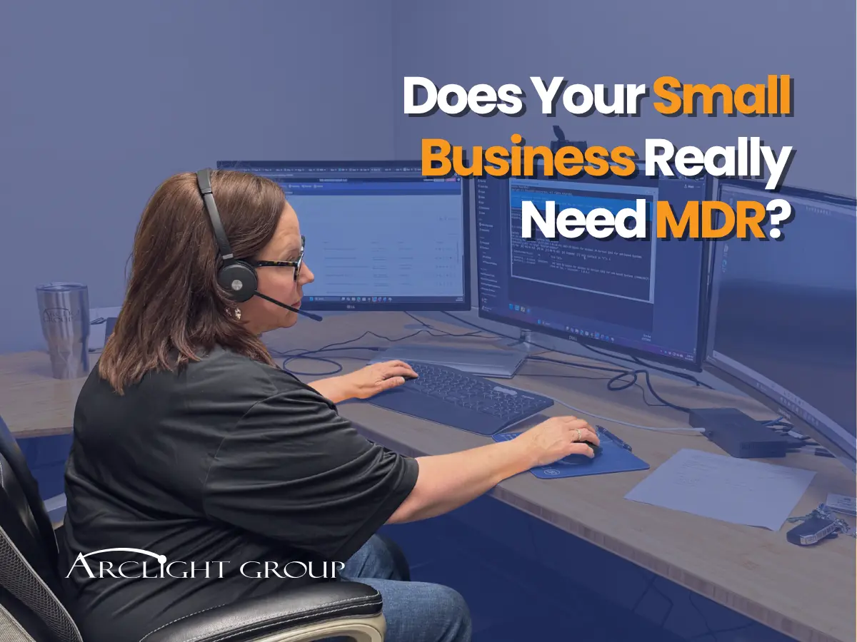 Woman with headset seated at a multi-monitor computer desk, blue overlay, promoting MDR for small business; reads 'Does Your Small Business Really Need MDR?' with ArcLight Group logo.